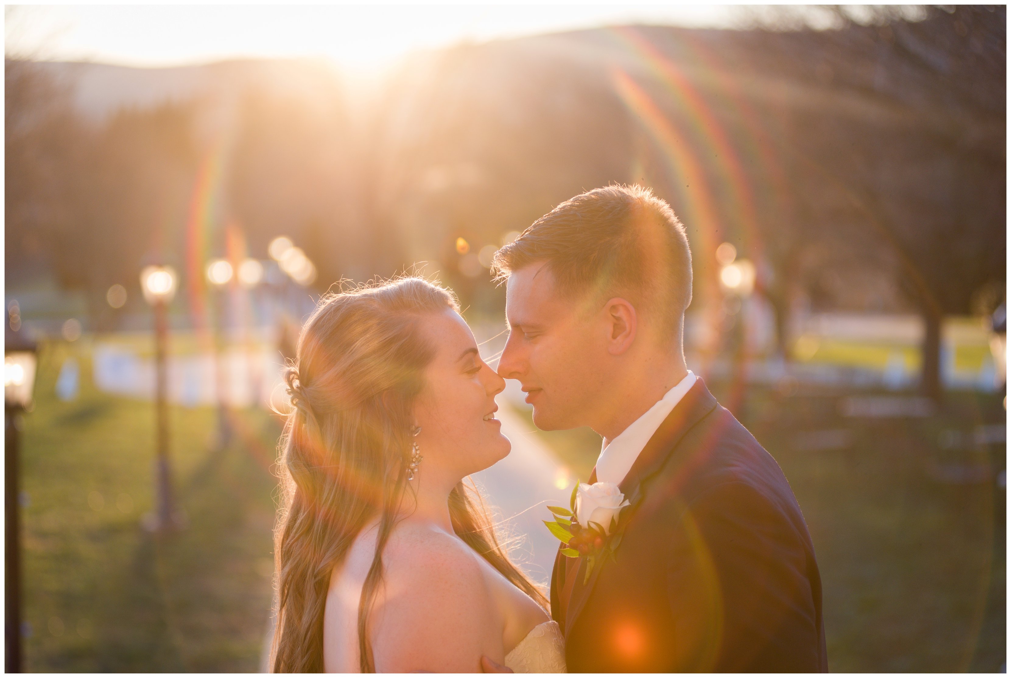 bride and groom kiss with sunset sunflare behind them at breaux vineyard wedding
