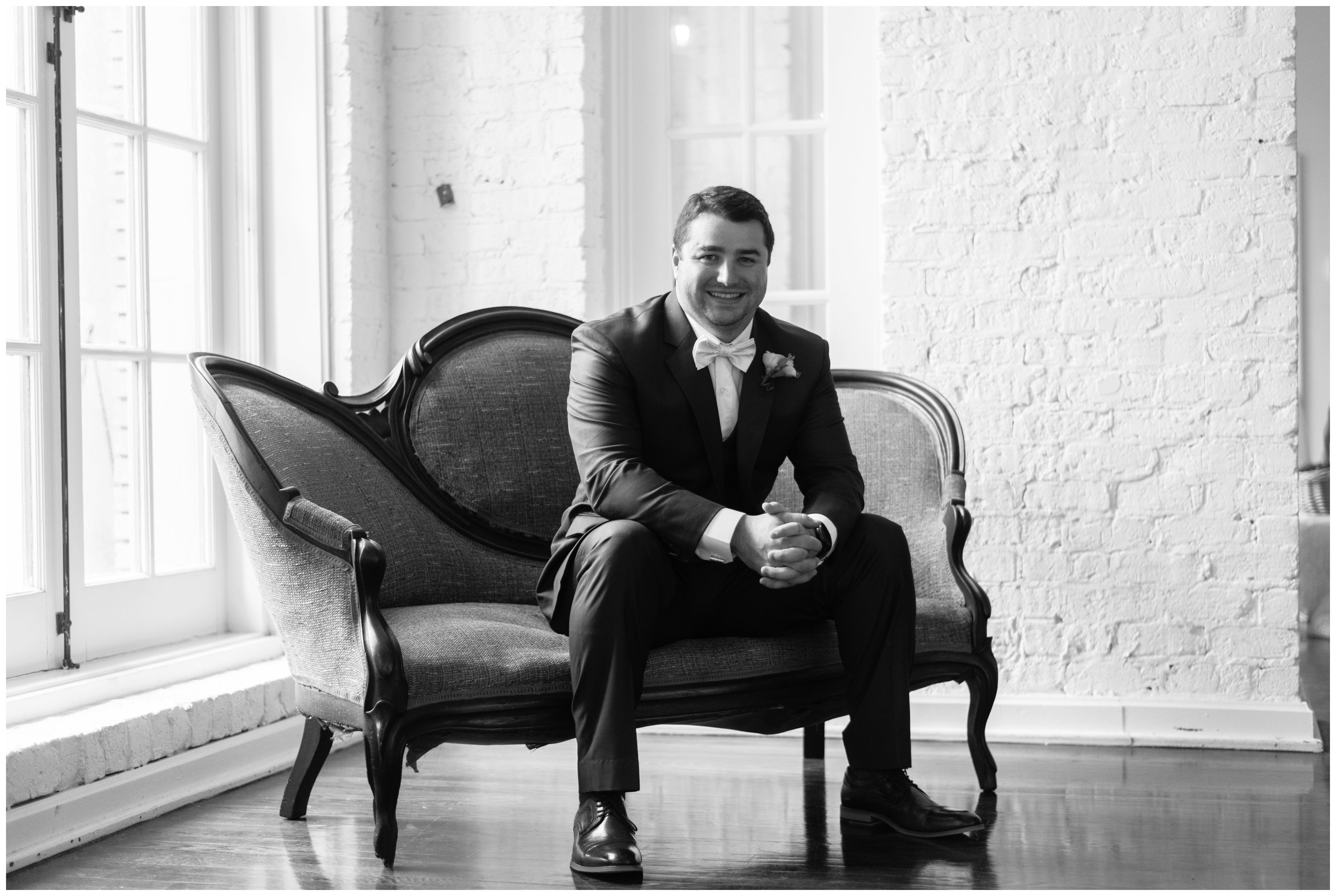 groom sitting on couch at historic post office by hampton roads wedding photographers