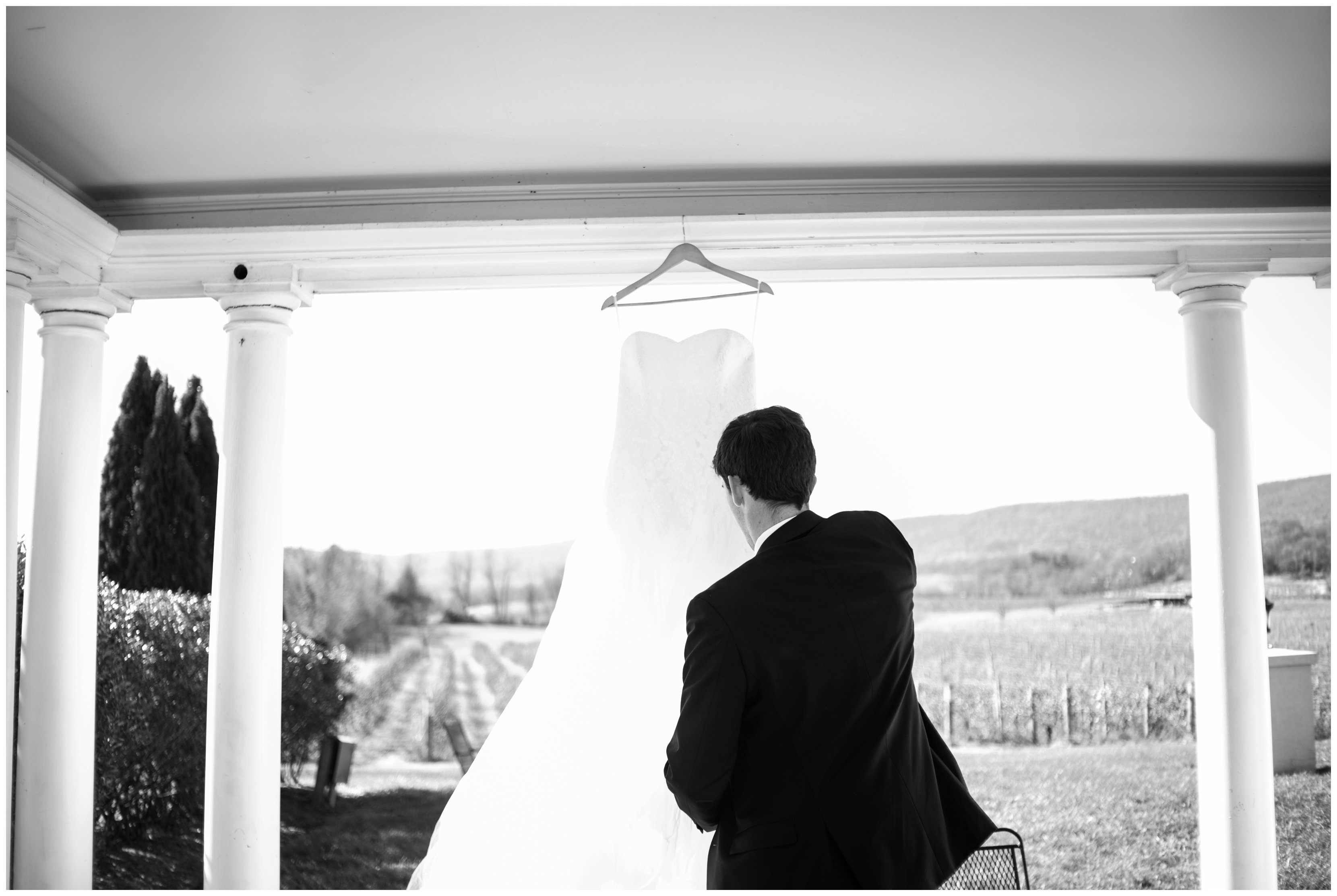 photographer hangs bridal dress at breaux vineyard wedding