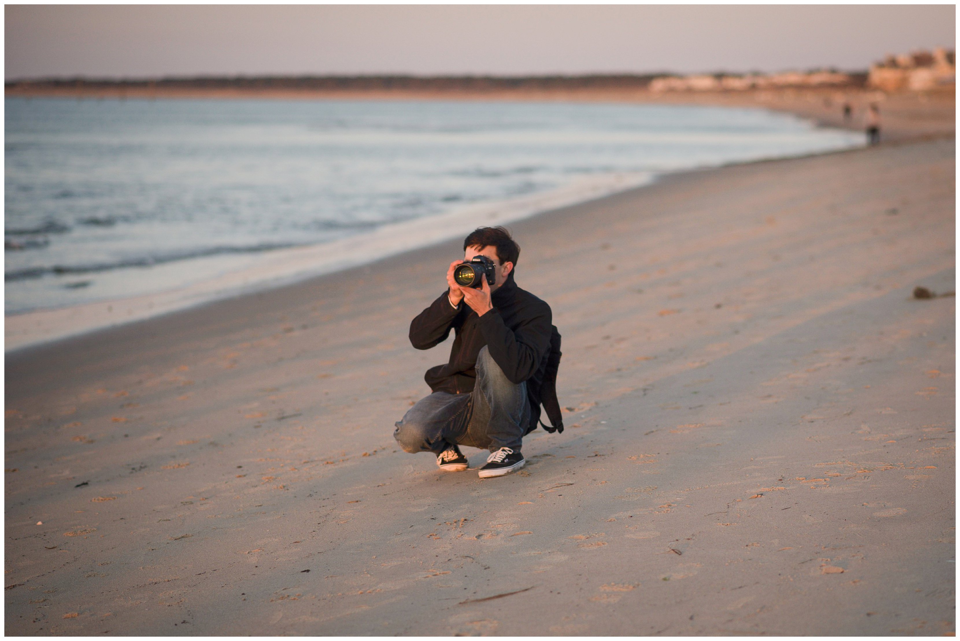virginia photographer crouches on beach to take photo of sunset