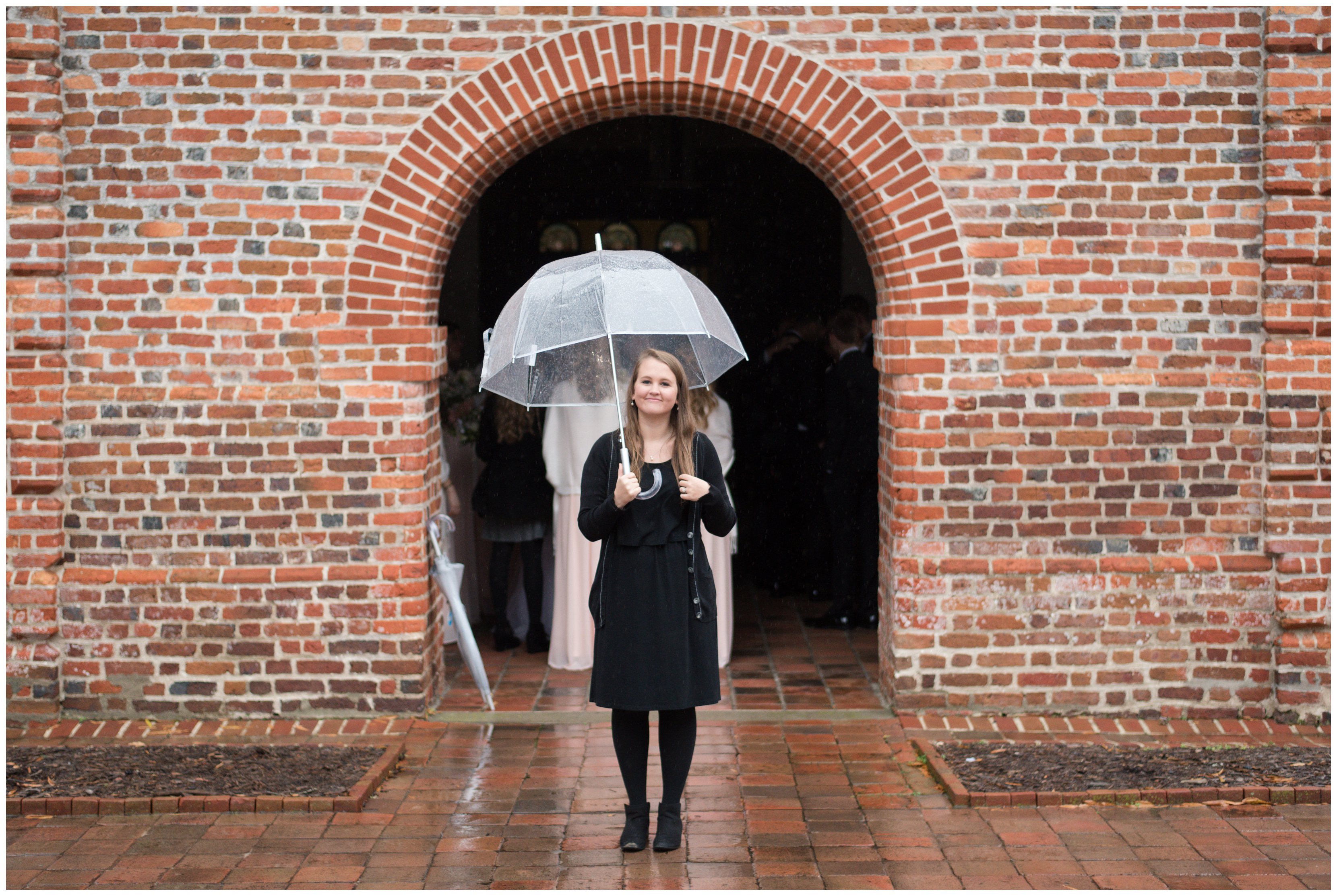 woman with umbrella standing in rain on wedding day in virginia